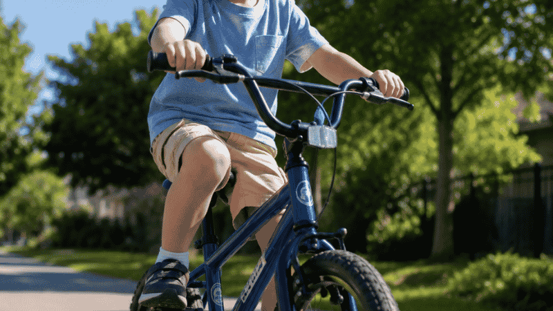 A confident 5-year-old child riding a two-wheel pedal bike on a sunny path wearing a helmet, smiling with joy
