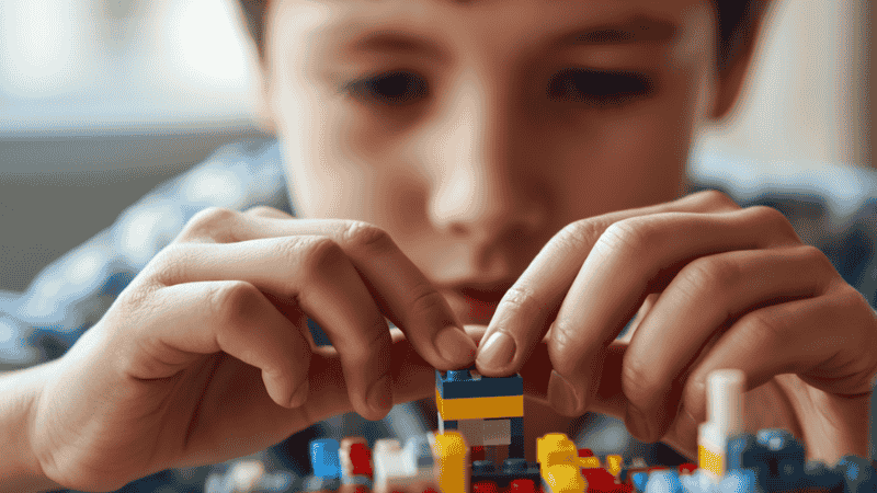 A close-up shot of a child's hands carefully attaching a small, printed LEGO brick onto a highly detailed LEGO Ideas display model.