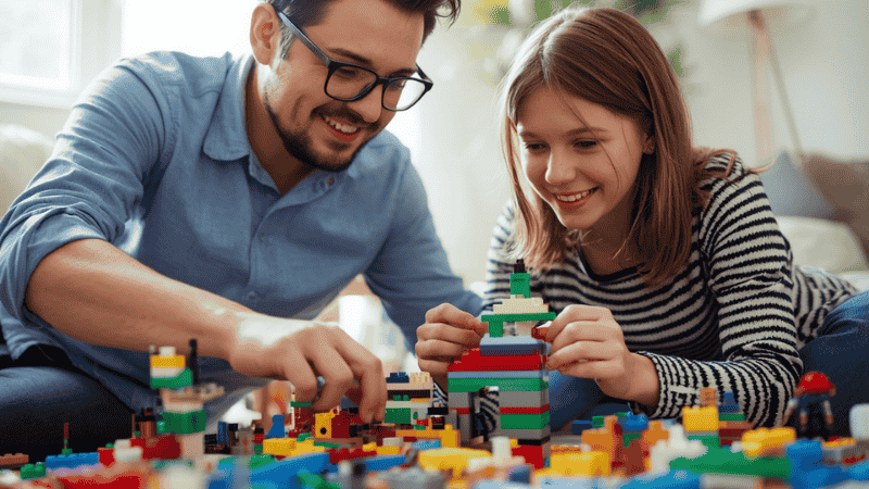 A parent and their teenage child working together on a large-scale LEGO Ideas project, sharing a moment of focused collaboration at the dining table.