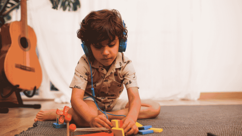 A young child using a screen-free audio player and headphones to listen to educational stories, promoting independent play.